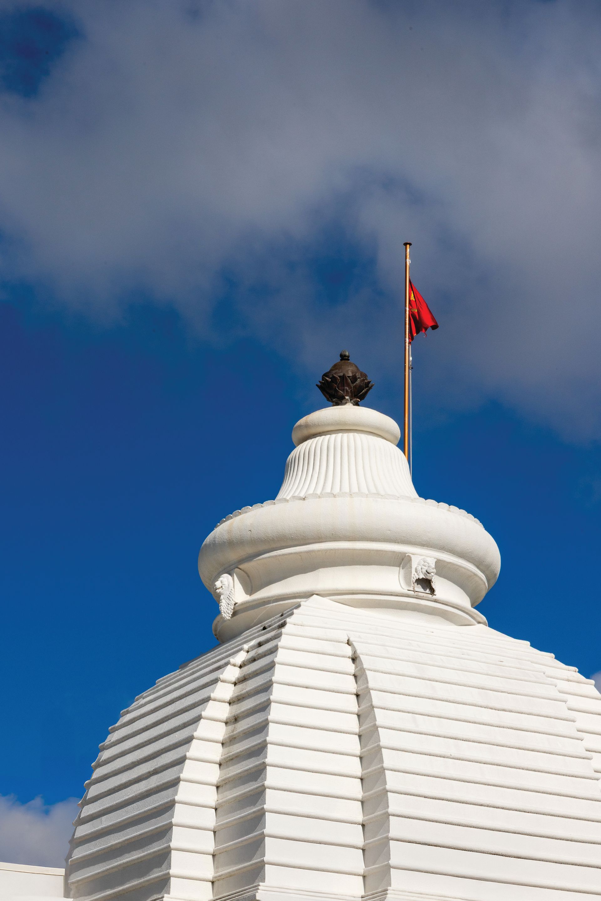 A white dome rood of a building with a red flag on top of it.