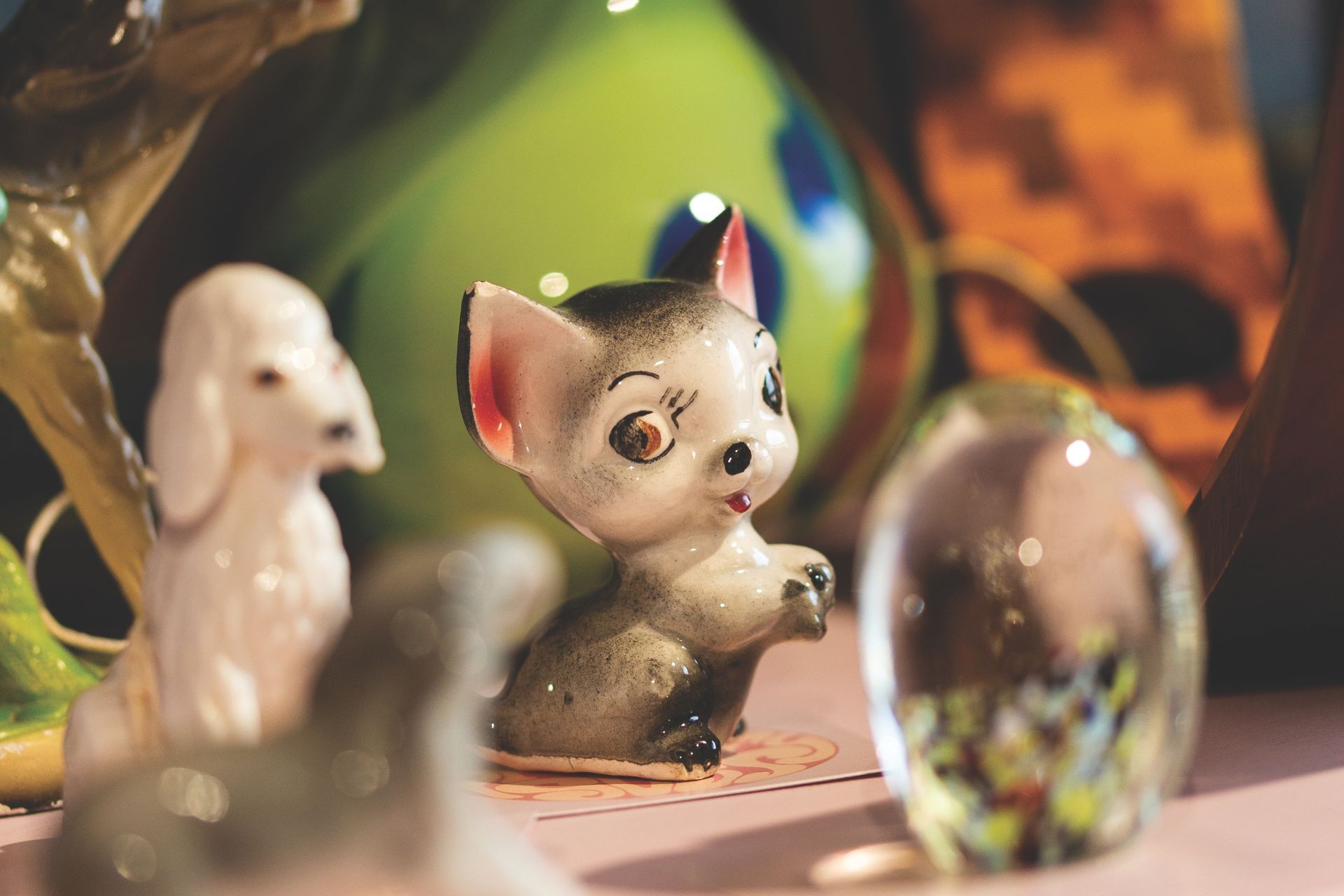 A shelf displaying ceramic animal figurines, a glass paperweight, and a green vase.