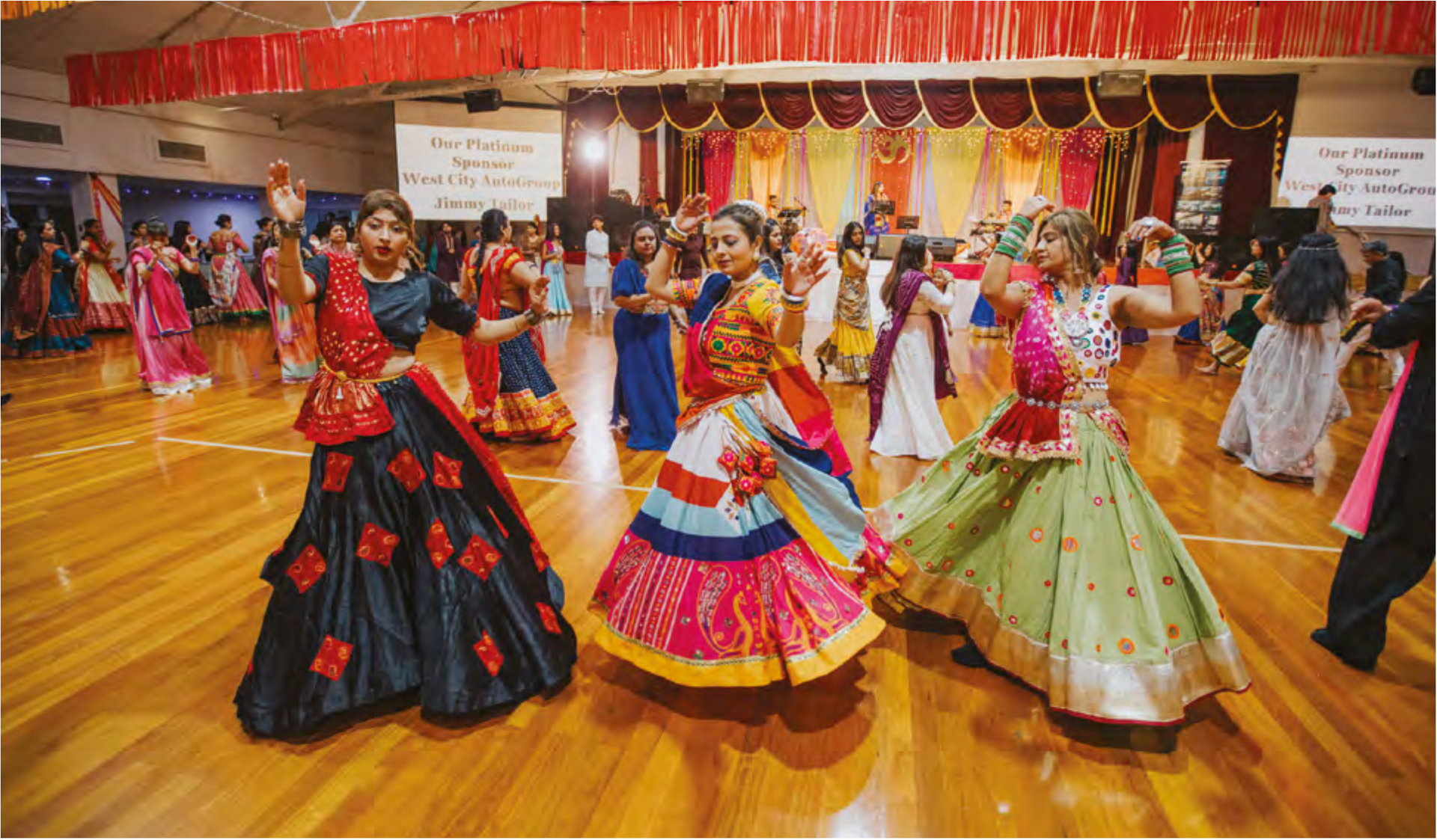 A group of people in colorful dresses are dancing in a room.
