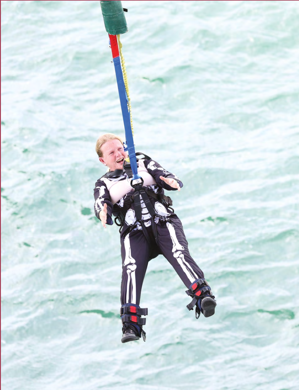 A woman bungee jumping over water.