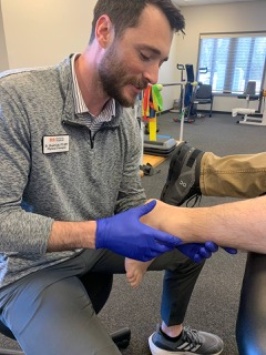 a man wearing blue gloves is examining a patient 's ankle