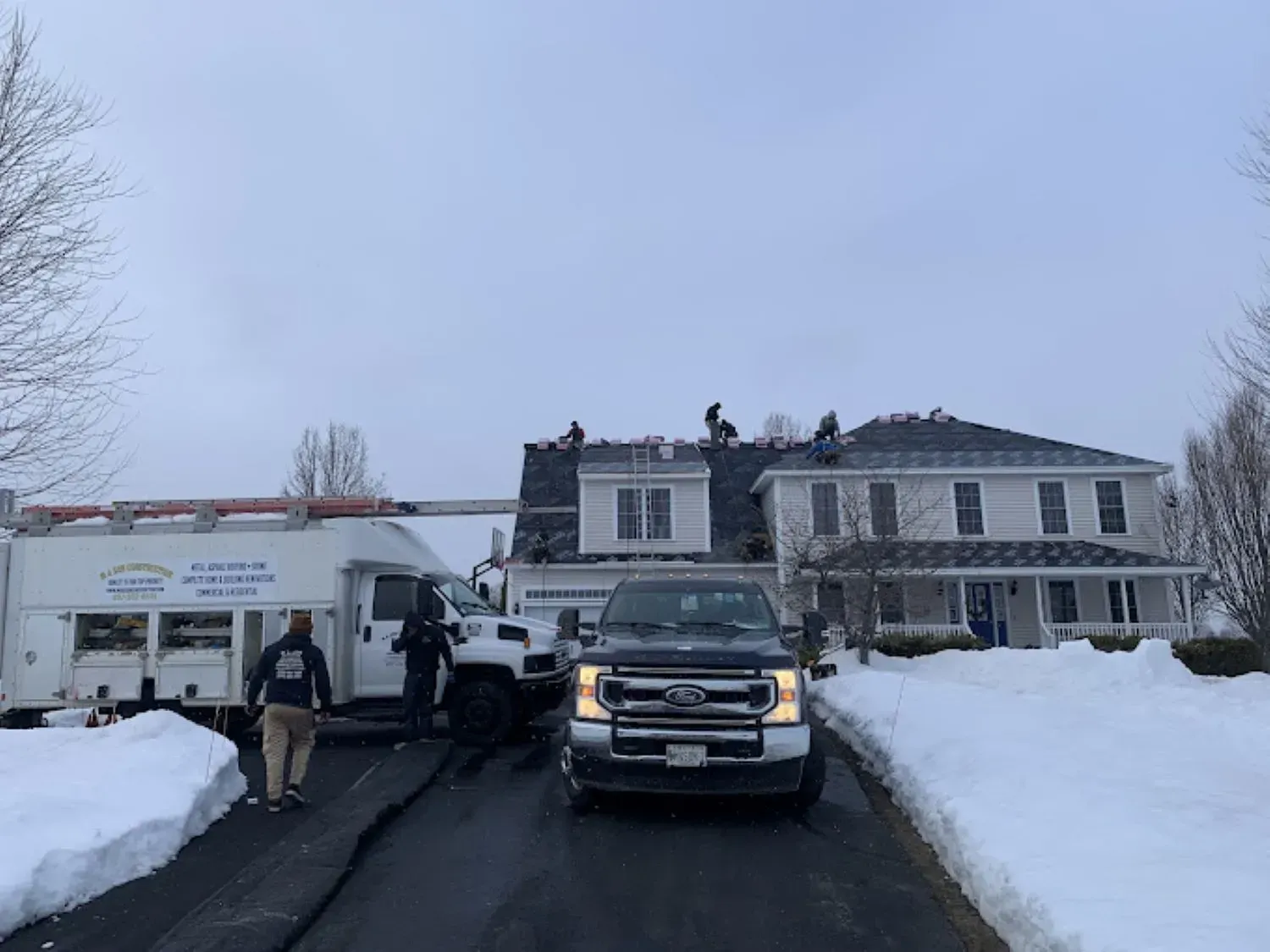A truck is parked in front of a house in the snow.