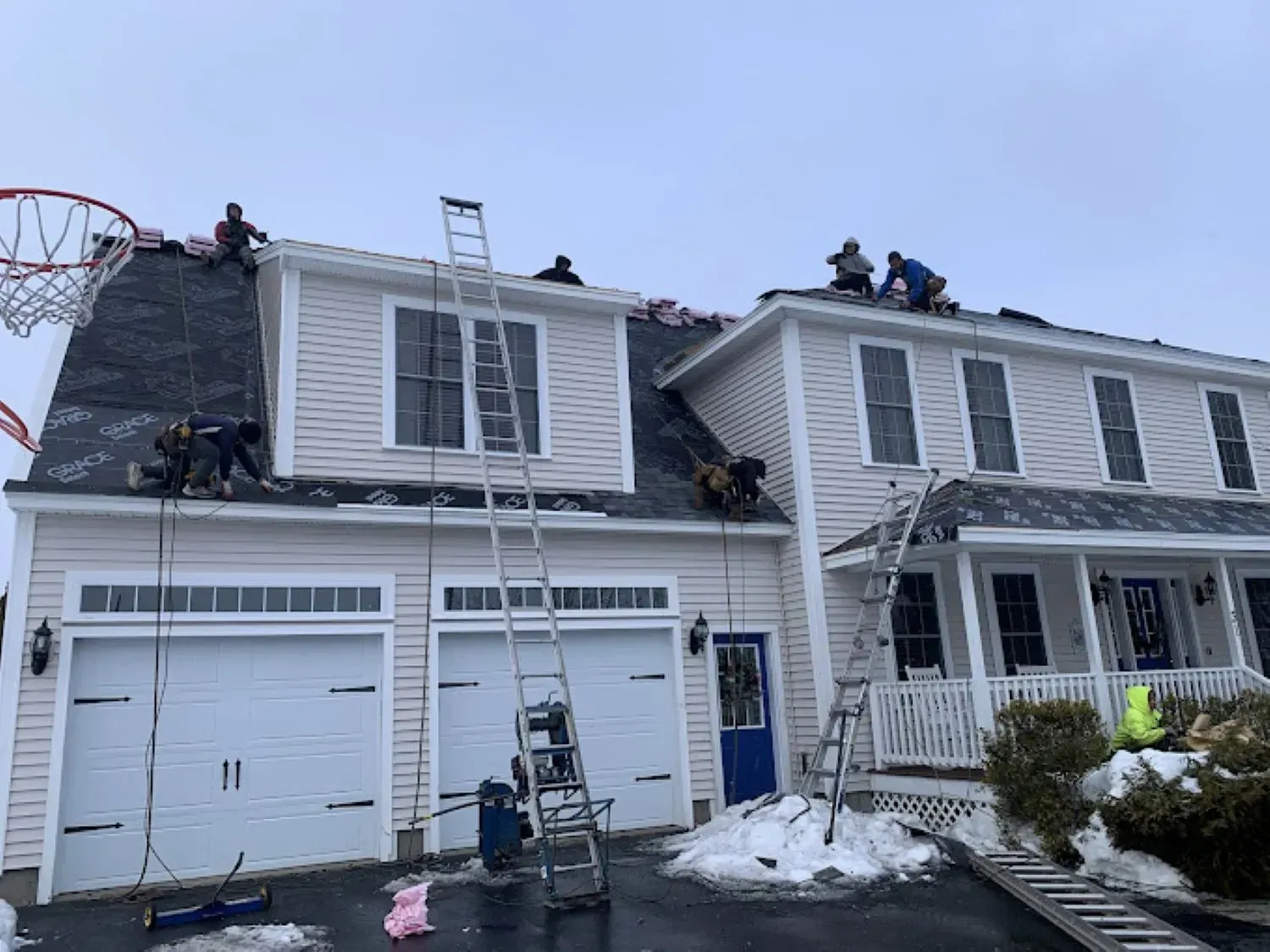 A group of people are working on the roof of a house.