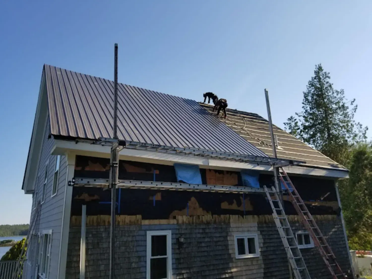 Two men are working on the roof of a house.