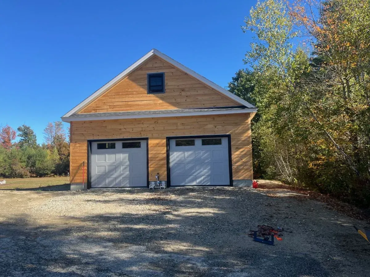 A wooden garage with two garage doors is being built.