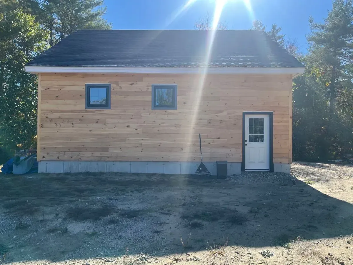 A small wooden house with a black roof and a white door.