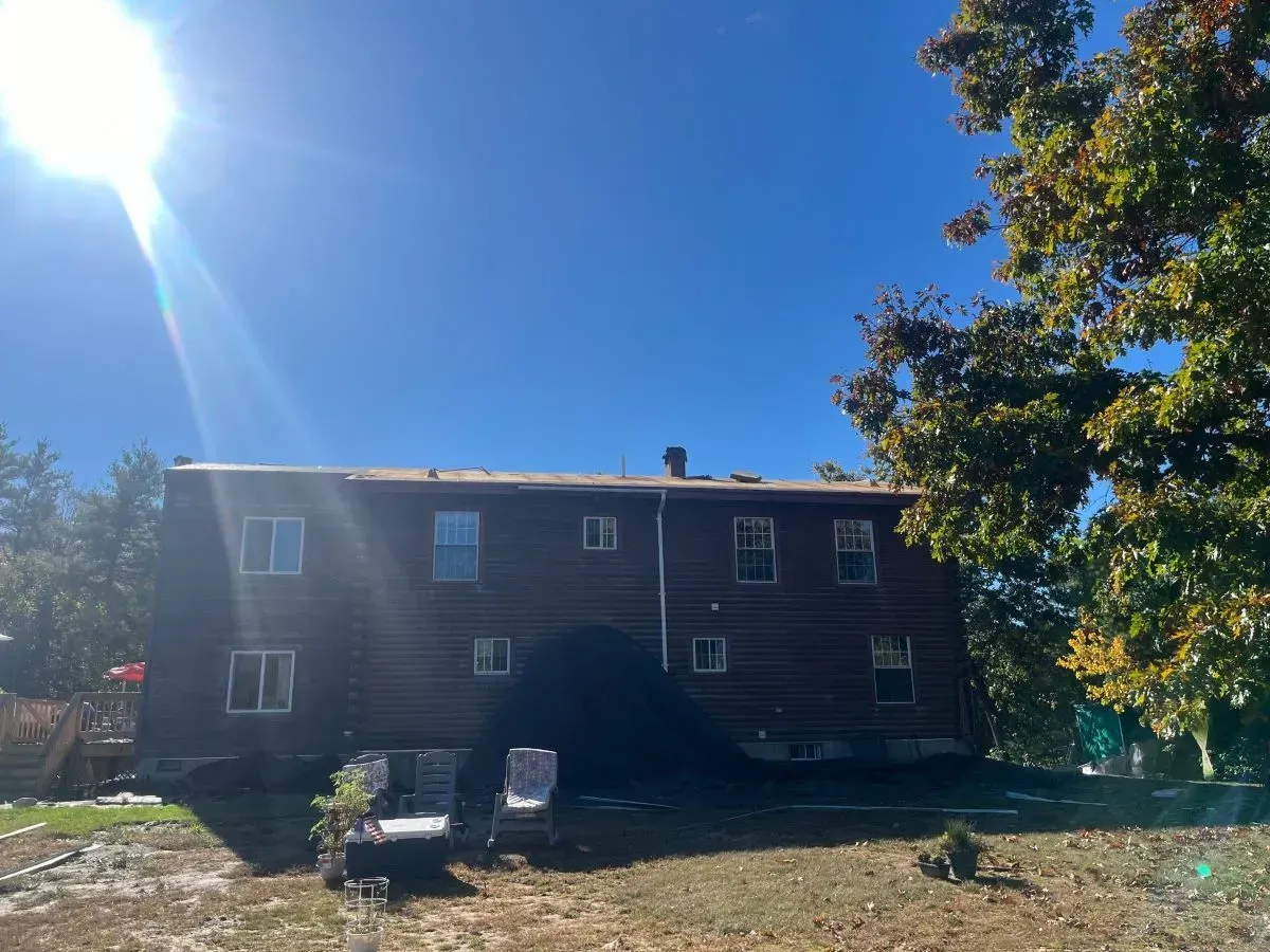A large wooden house is sitting on top of a dirt field.