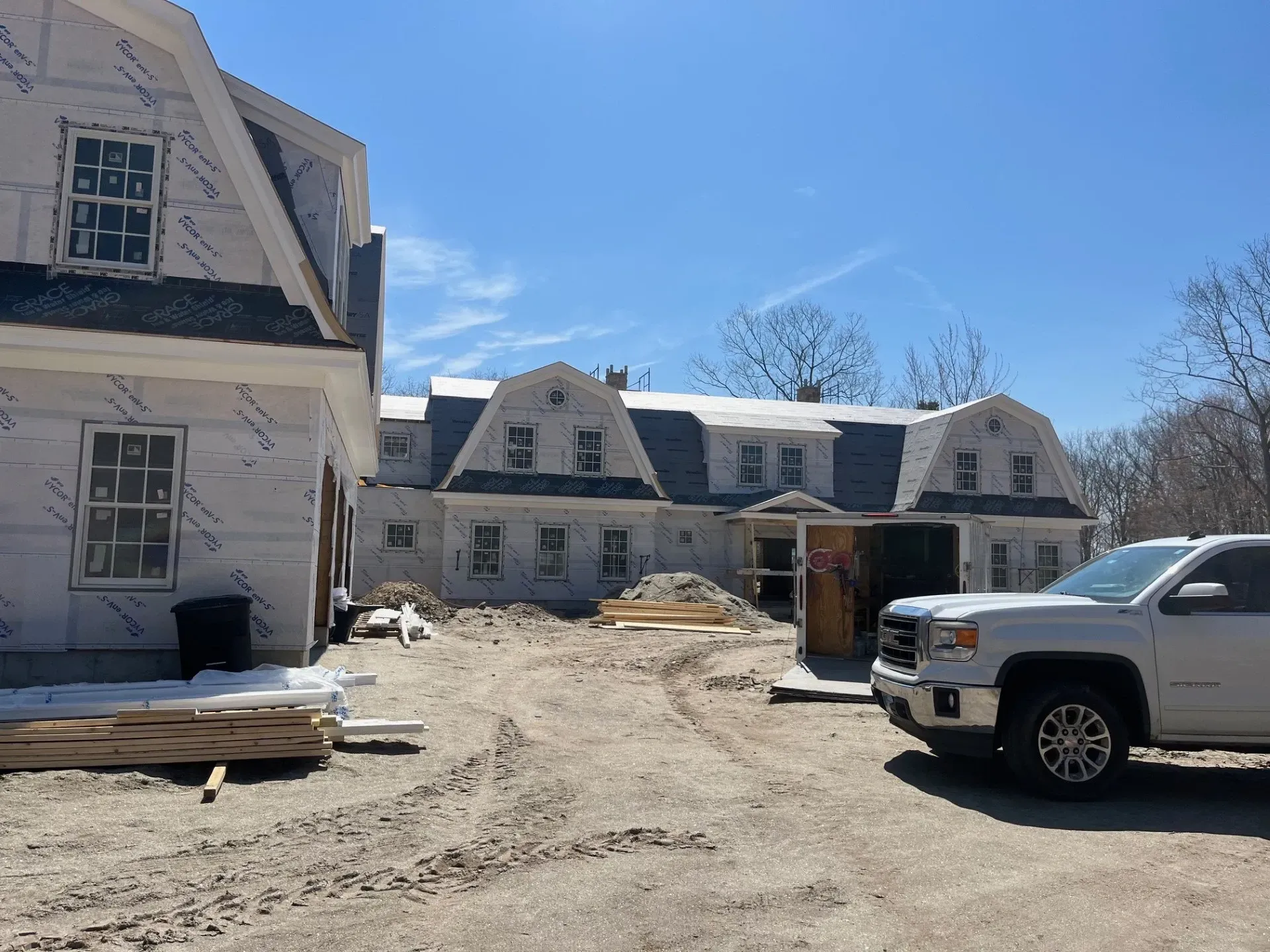 A white truck is parked in front of a house under construction.