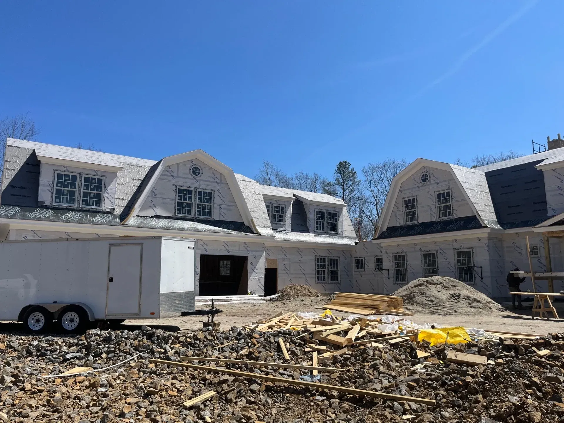 A trailer is parked in front of a house under construction.