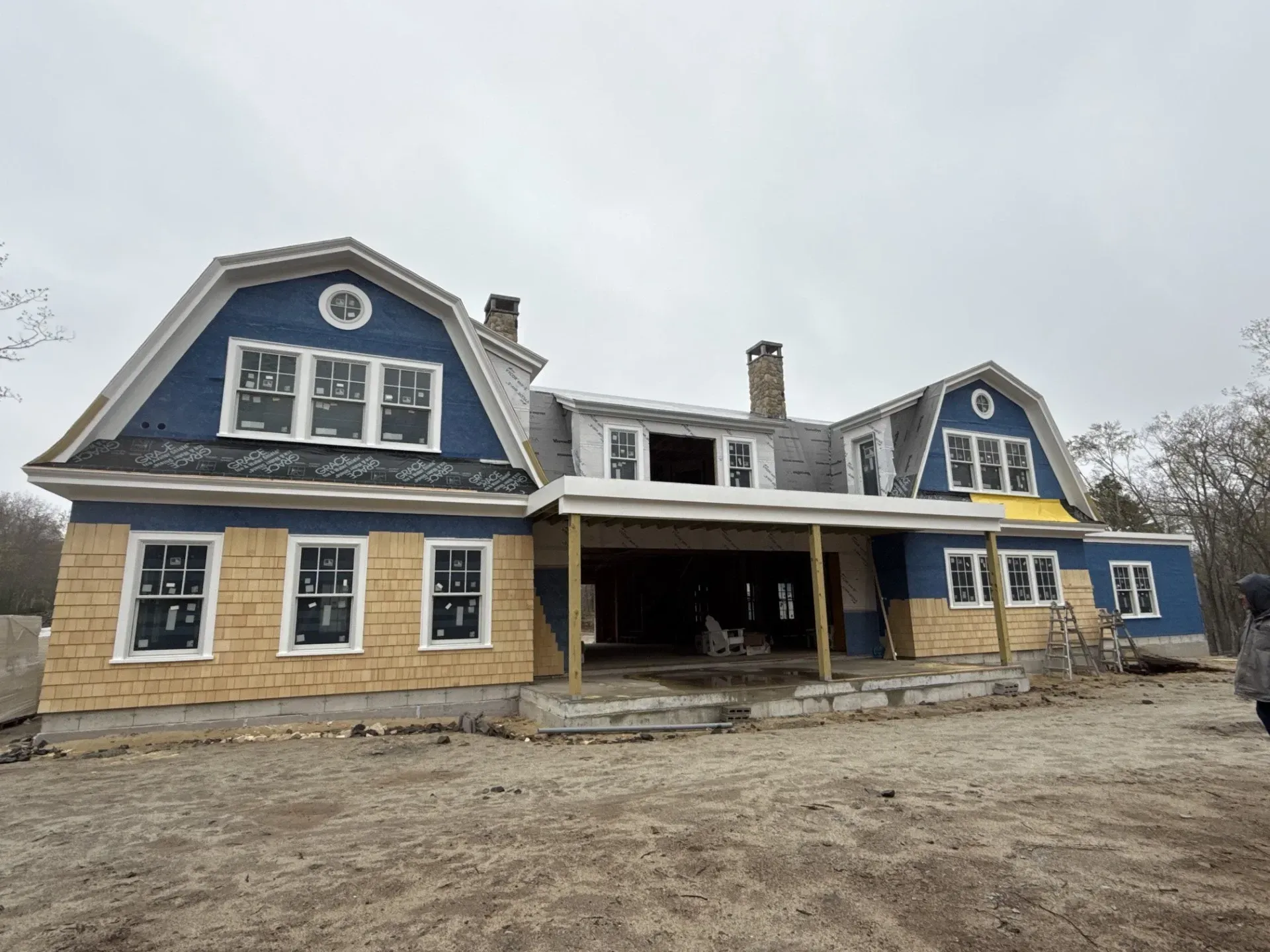 A large house is being built in a dirt field.