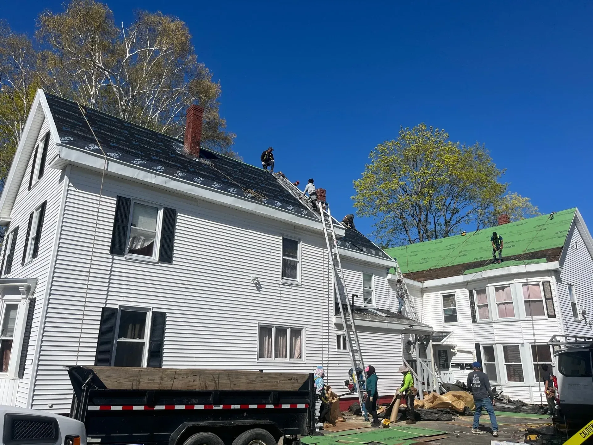 A group of people are working on the roof of a house.