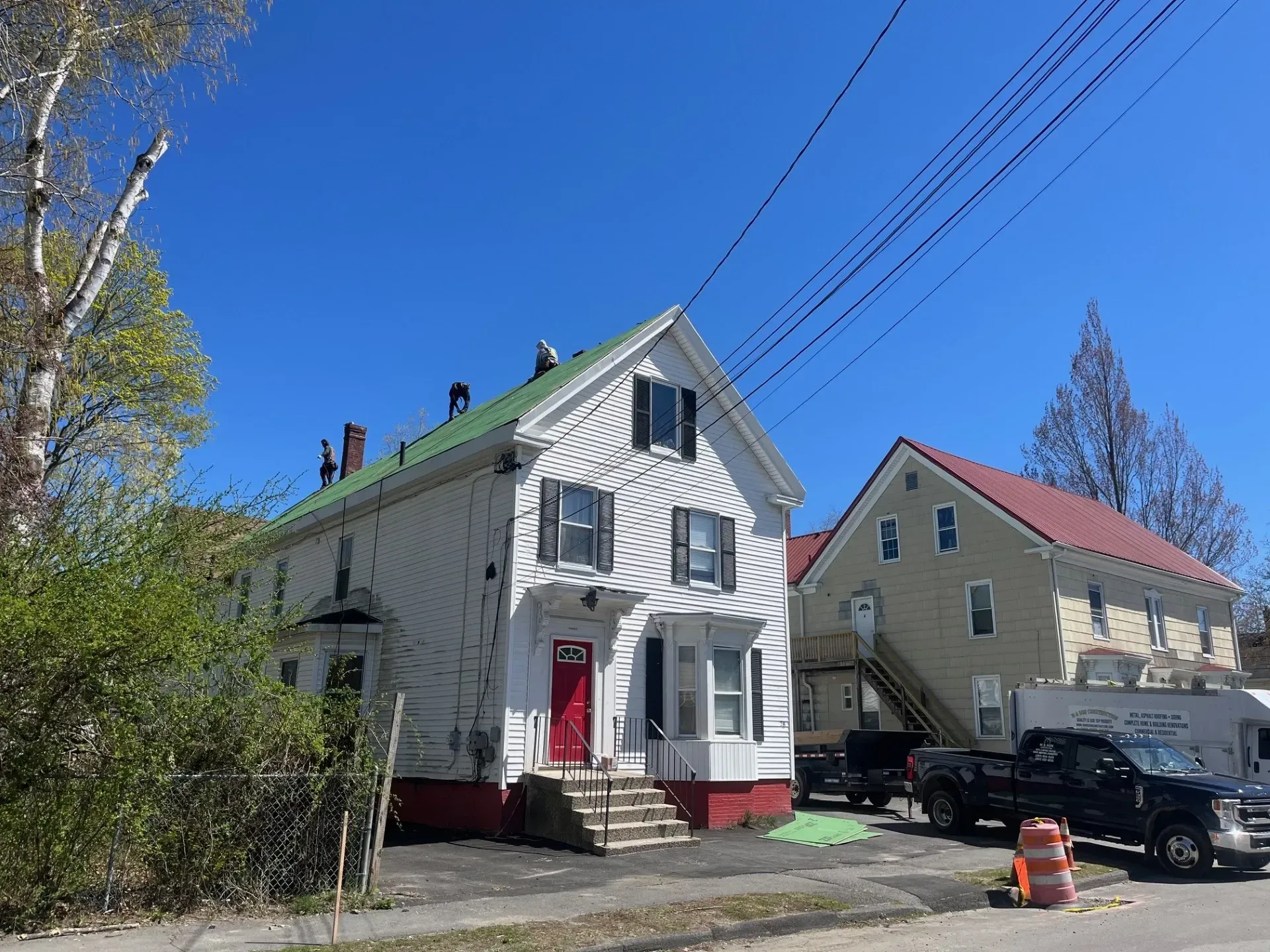 A white house with a green roof is sitting next to a yellow house.