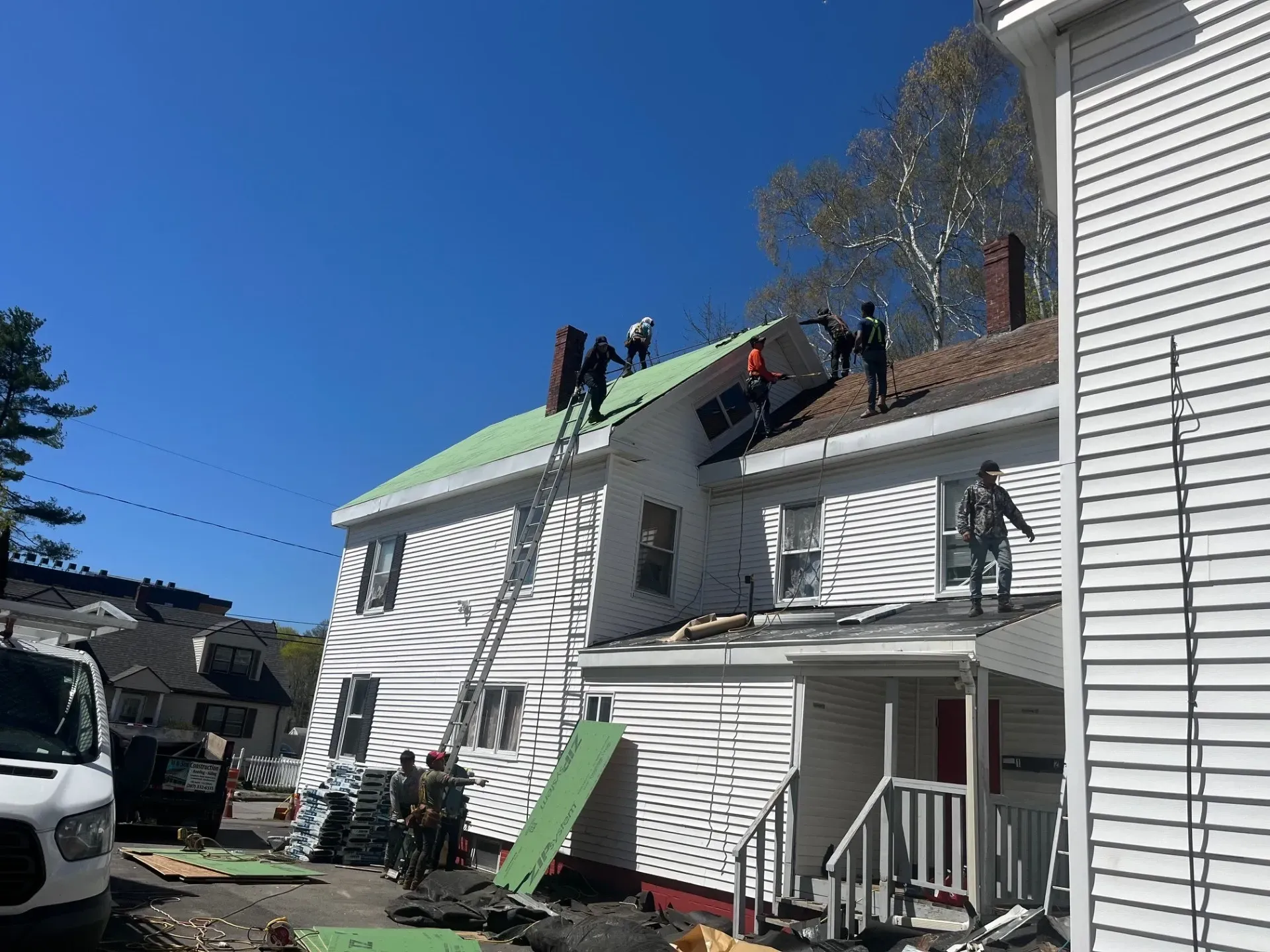 A group of people are working on the roof of a house.