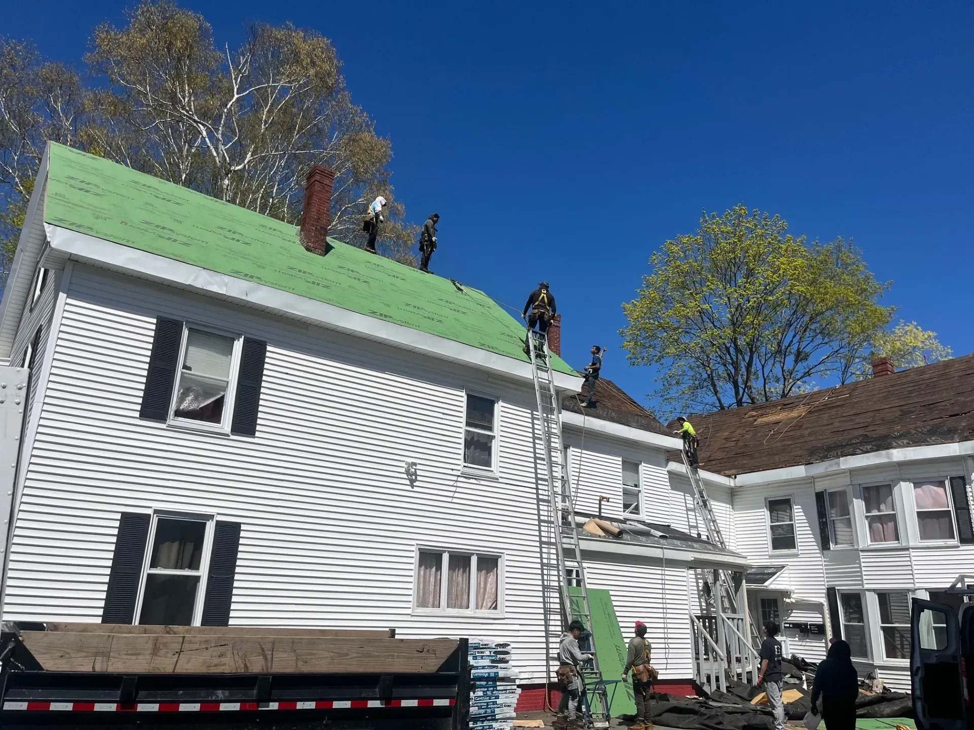 A group of people are working on the roof of a house.