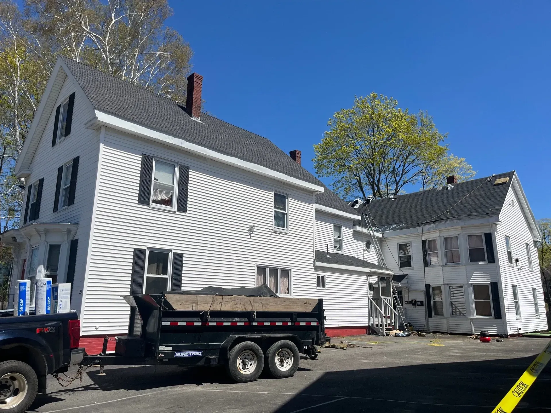 A dumpster is parked in front of a white house.