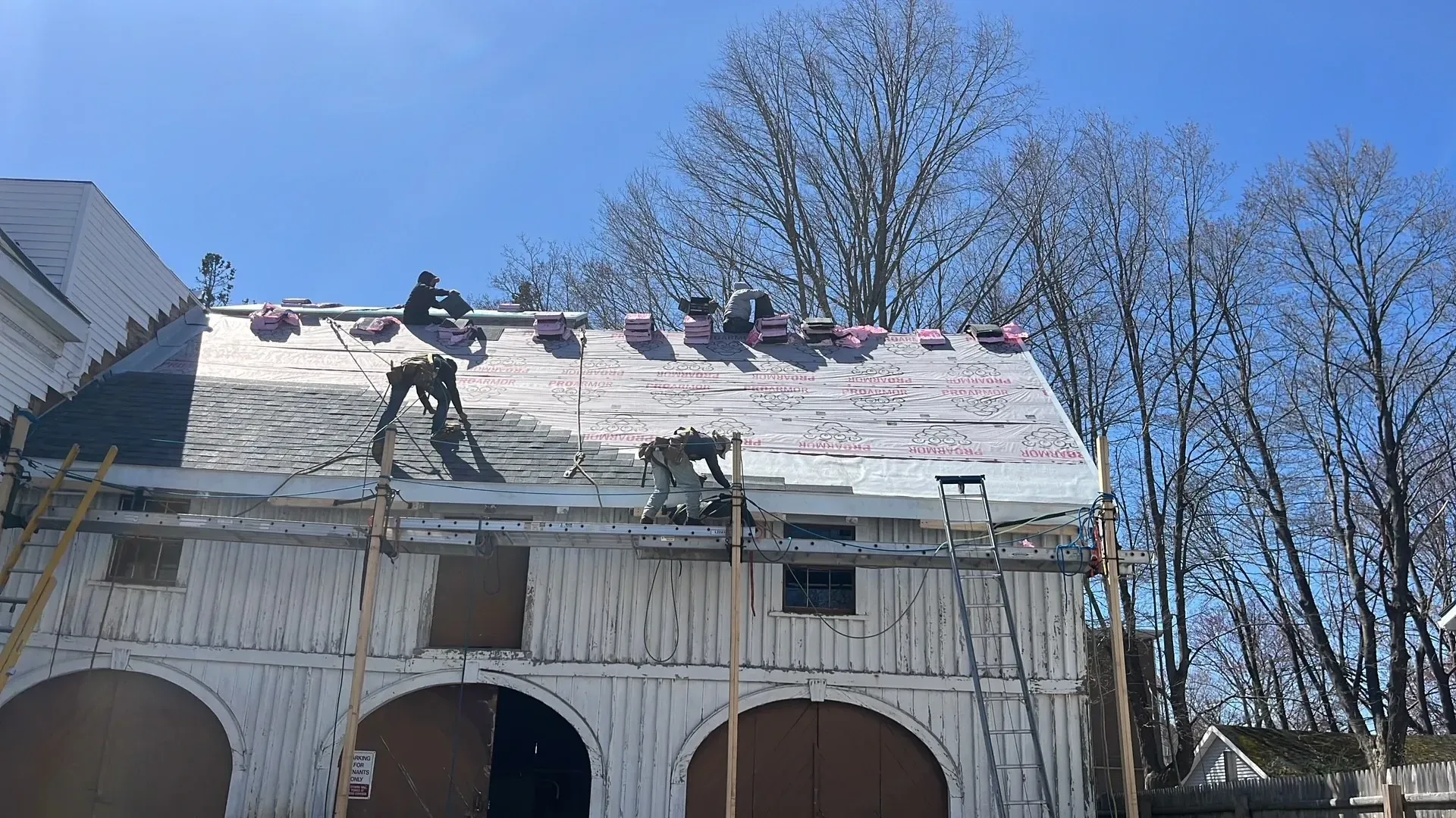 A group of people are working on the roof of a barn.