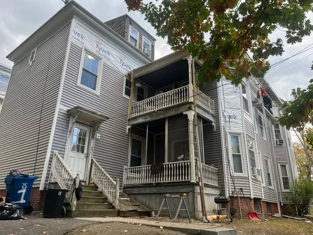 A large house with a porch and stairs is being remodeled.