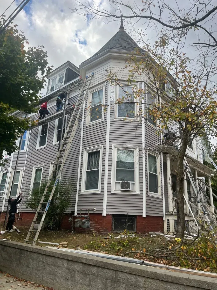 A group of people are painting the side of a house.