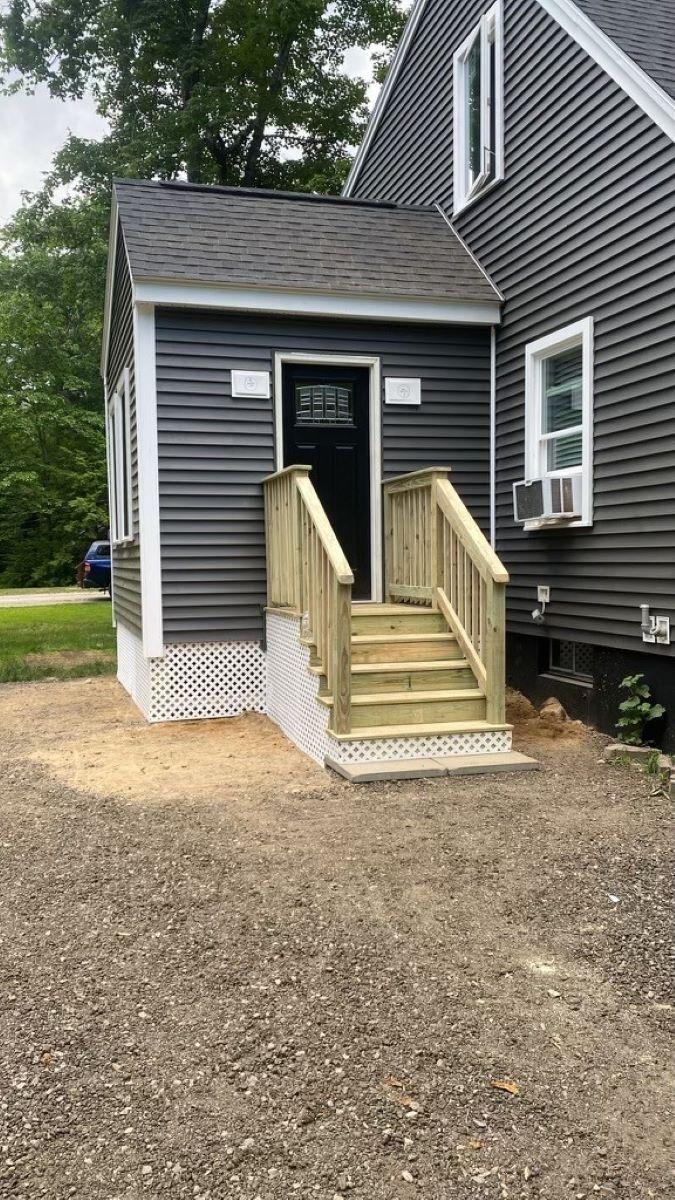 A house with a wooden deck and stairs leading to the front door.