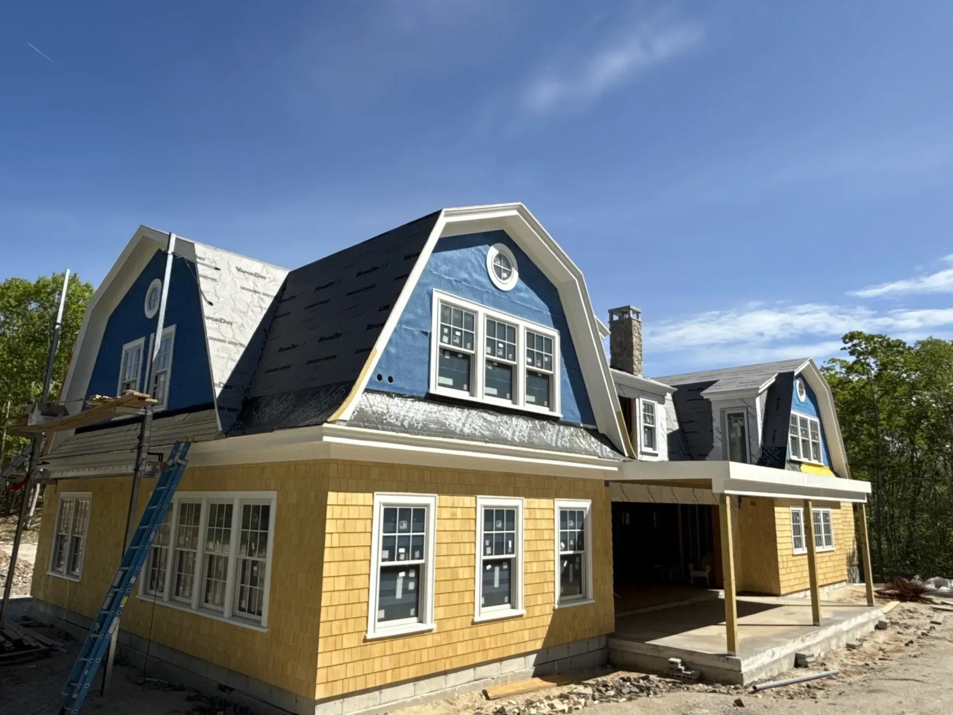 A yellow house with a blue roof is being built