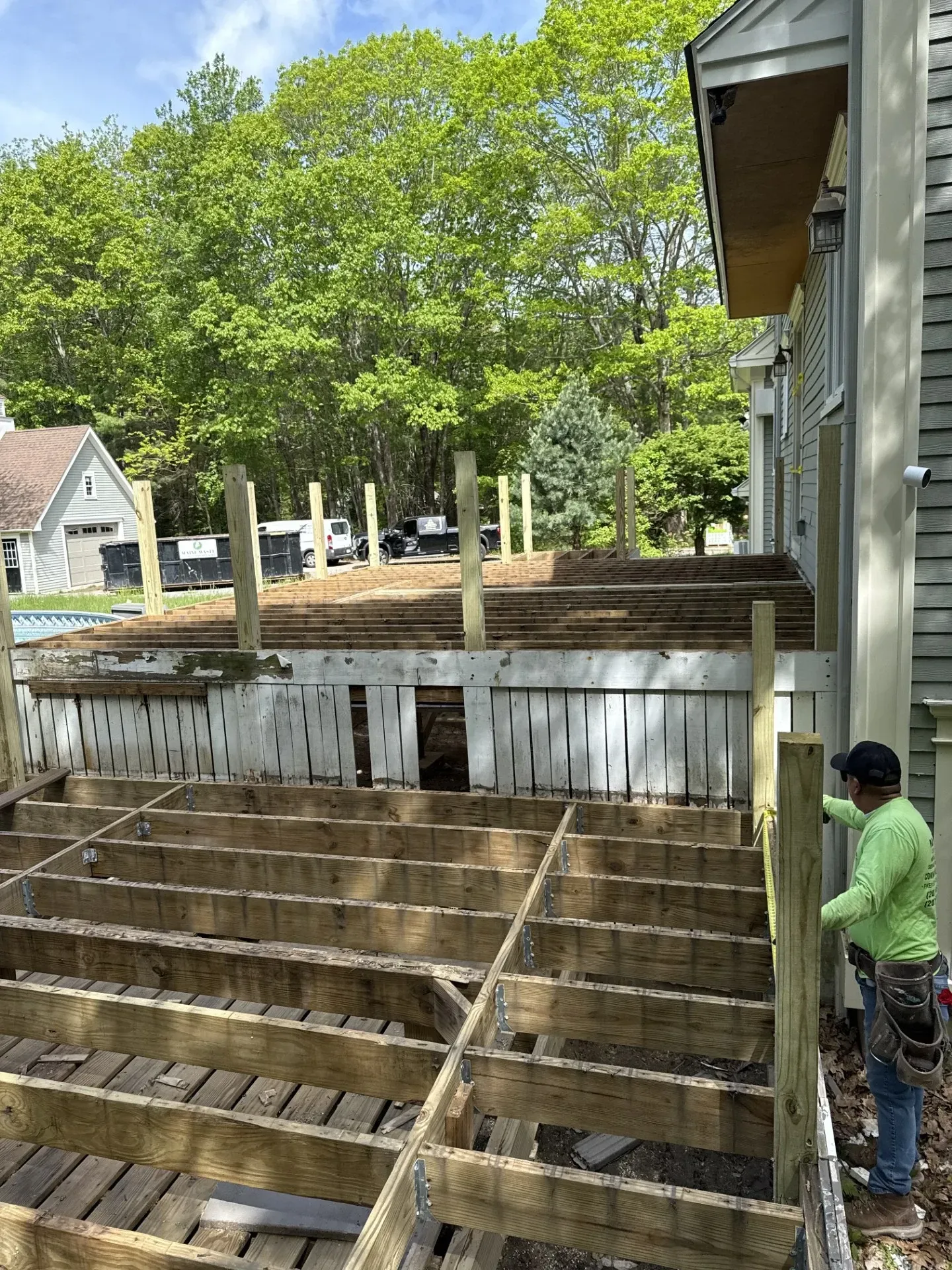 A man is working on a wooden deck in front of a house.