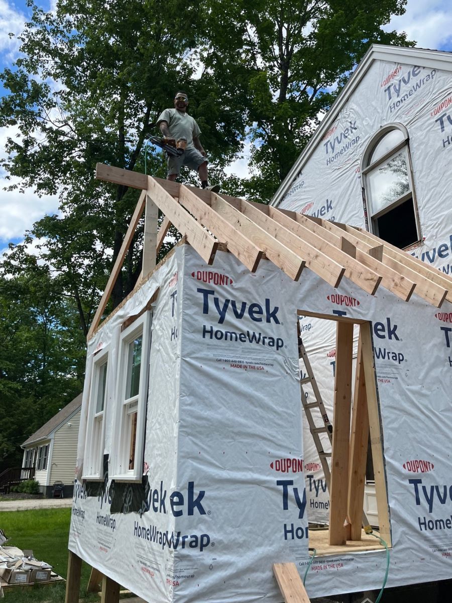 A man is standing on top of a house under construction.