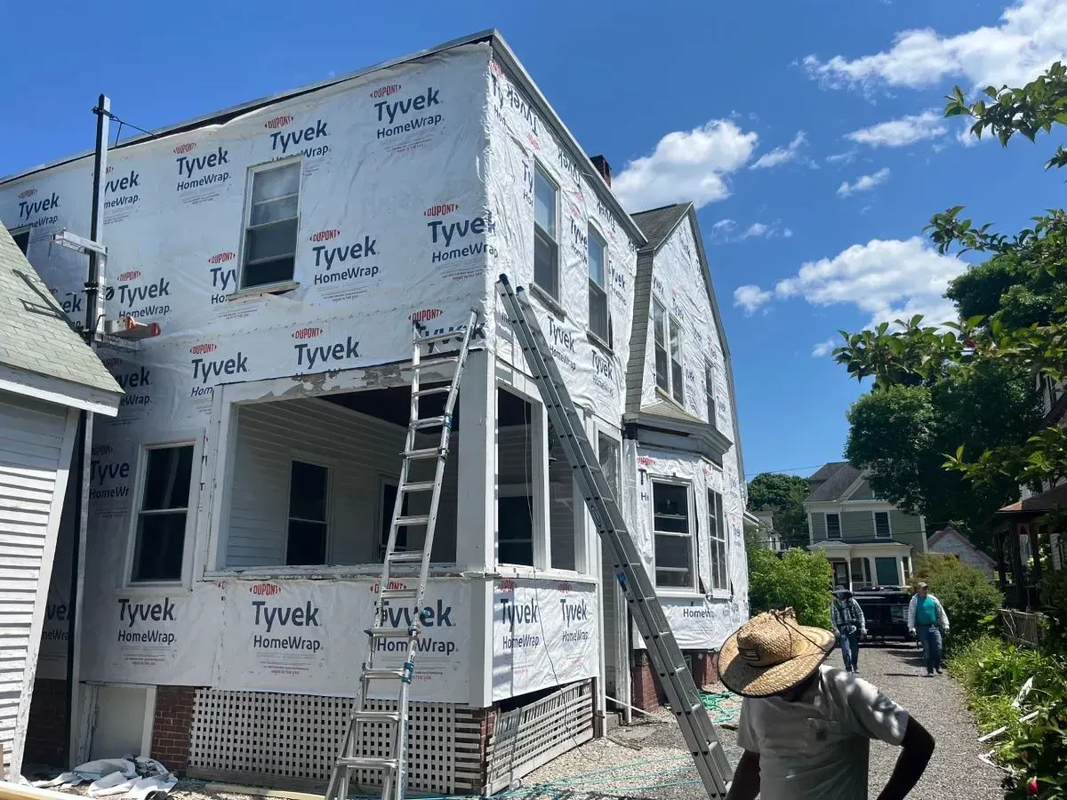 A man is standing in front of a building with a ladder.