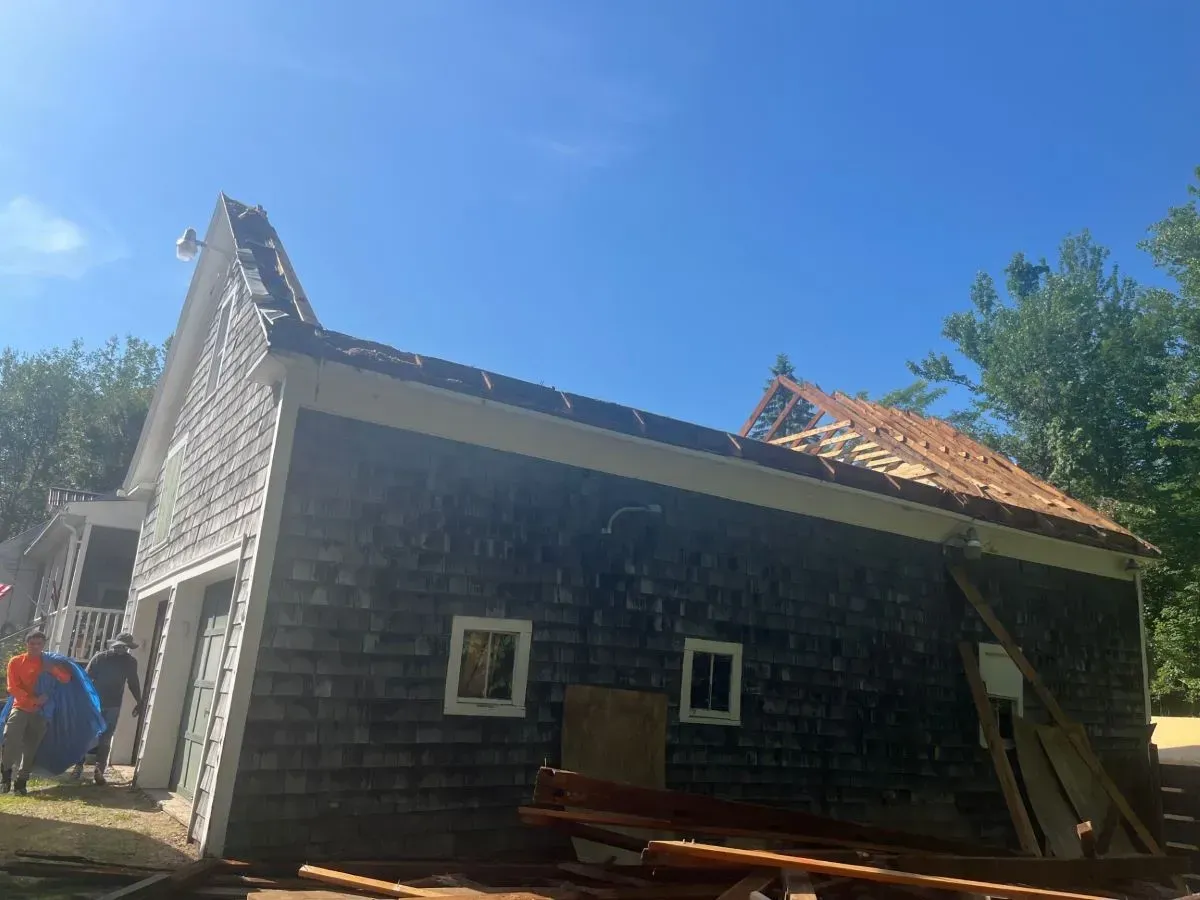 A house with a roof that is being built and a blue sky in the background.