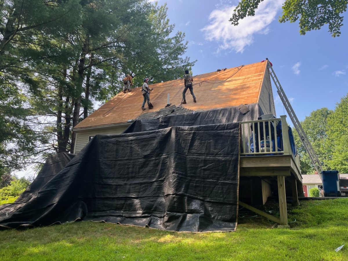 A group of people are working on the roof of a house.