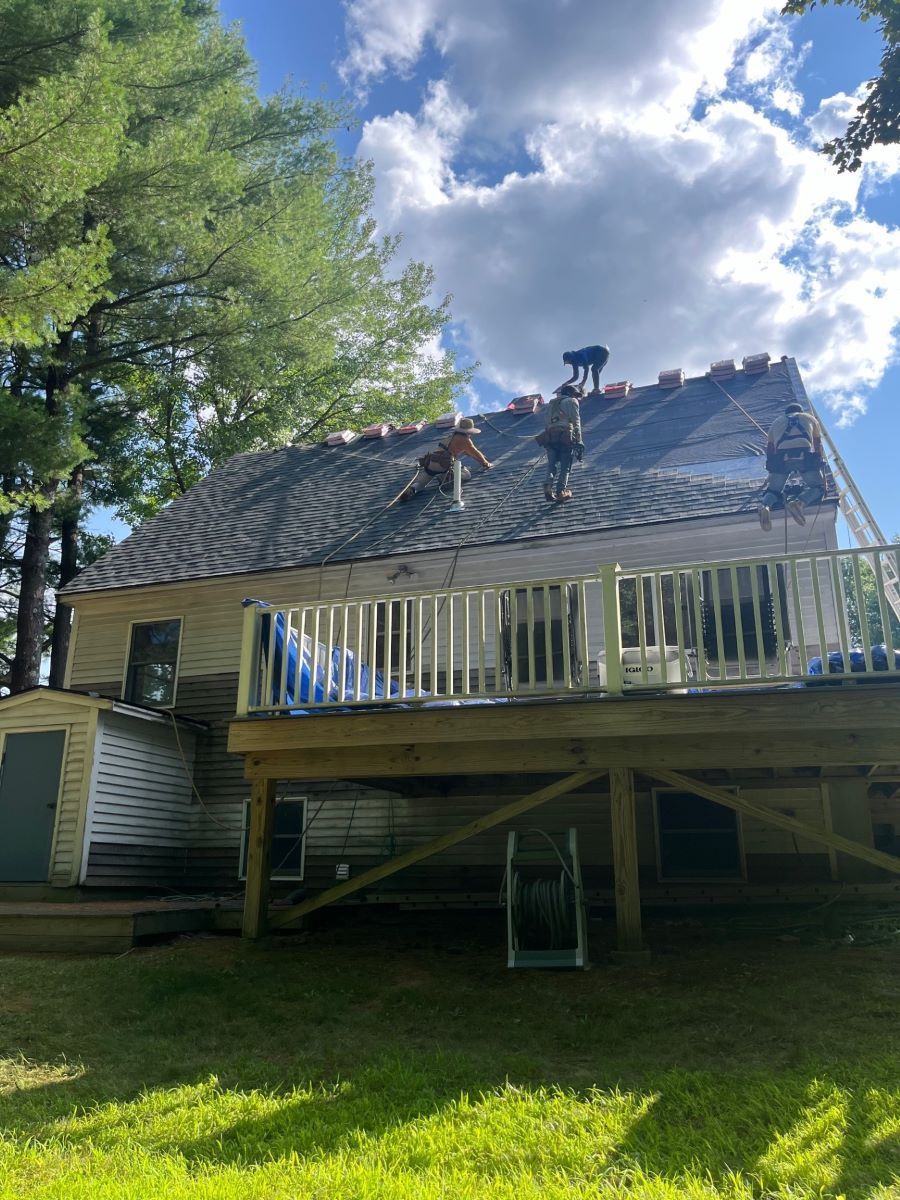 A man is working on the roof of a house with a deck.