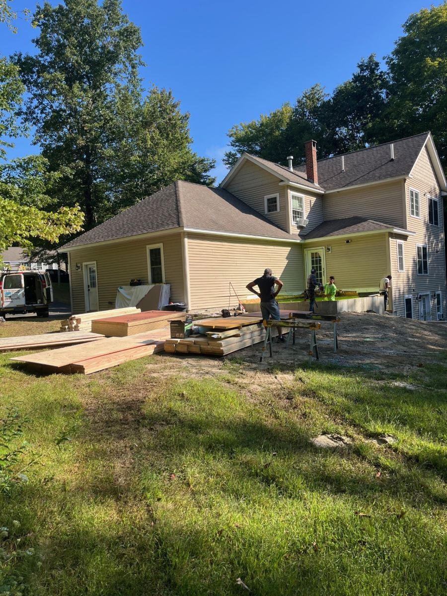 A man is standing in front of a house that is being remodeled.