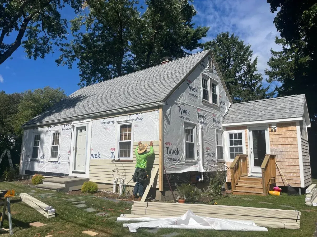 A man is standing in front of a house that is being remodeled.