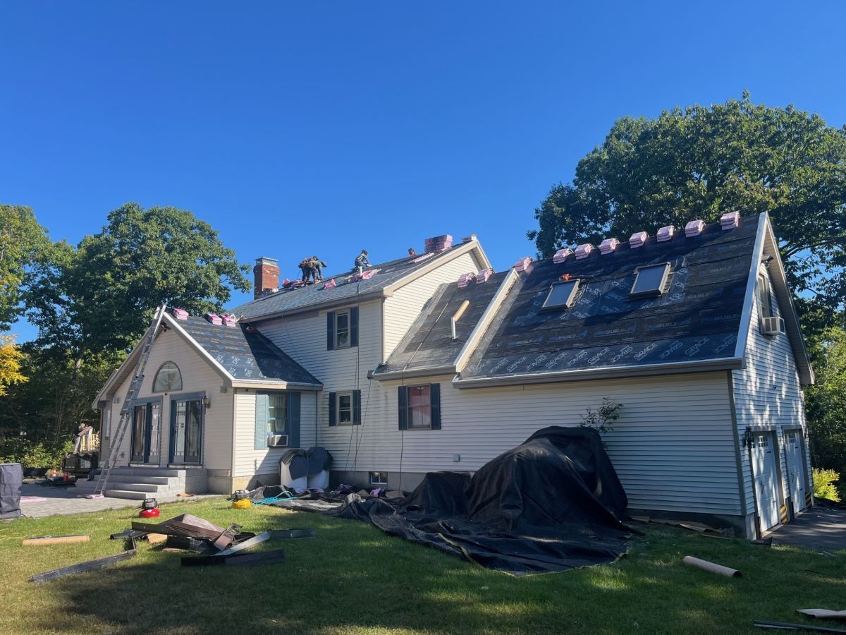 A large white house with a slate roof is being remodeled.