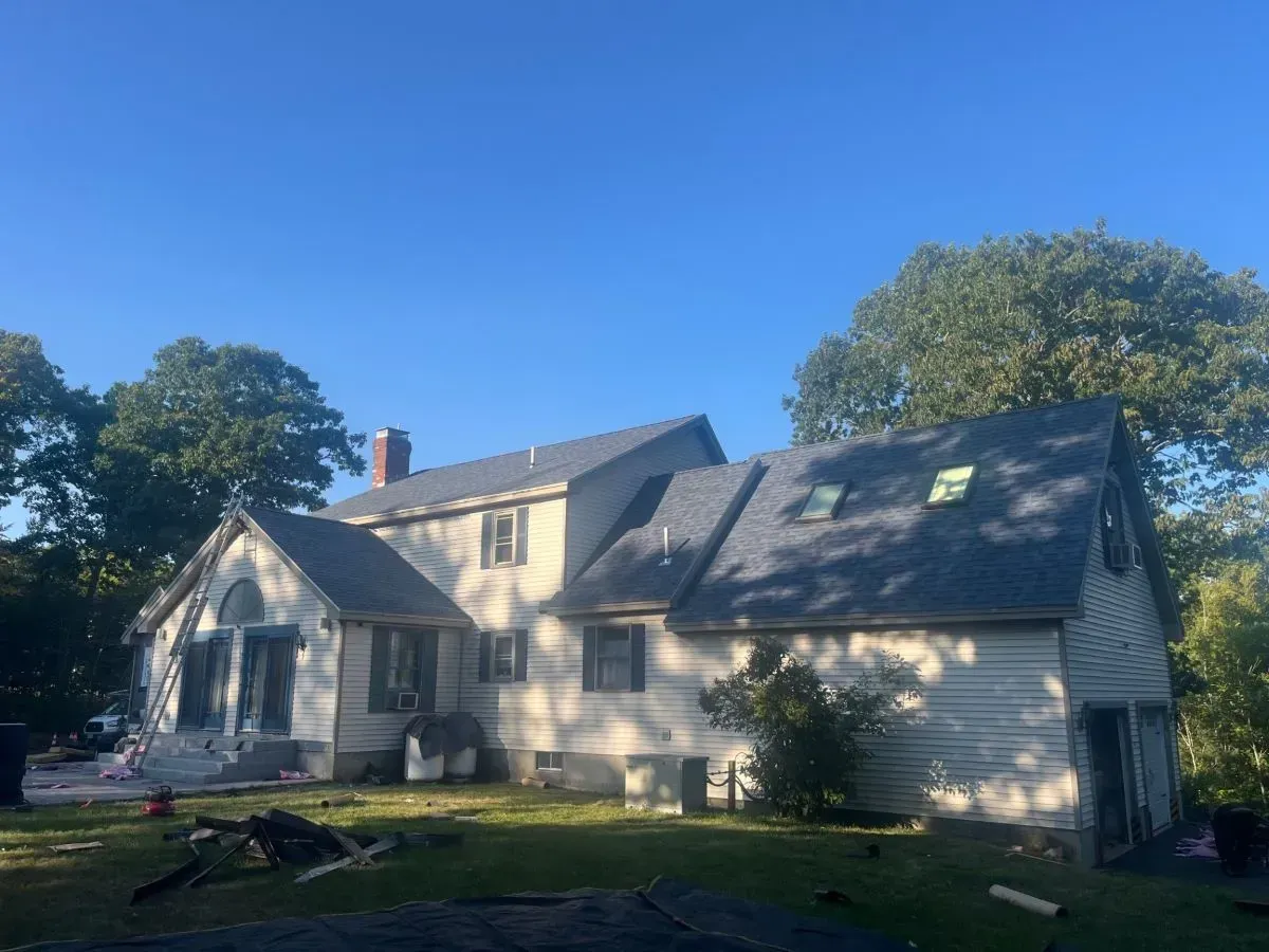 A large white house with a gray roof and a blue sky in the background.