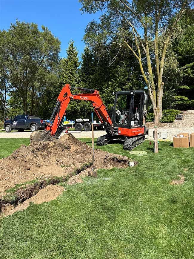 A red excavator is digging a hole in a yard.