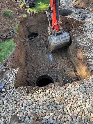 A red excavator is digging a hole in the ground.