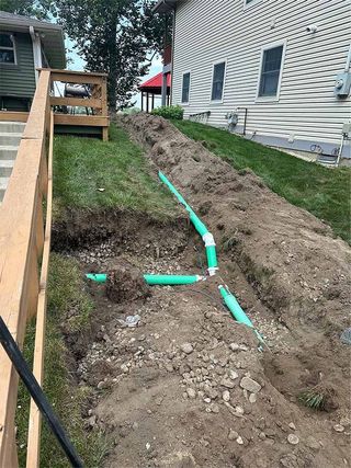 A drainage system is being installed on the side of a house.