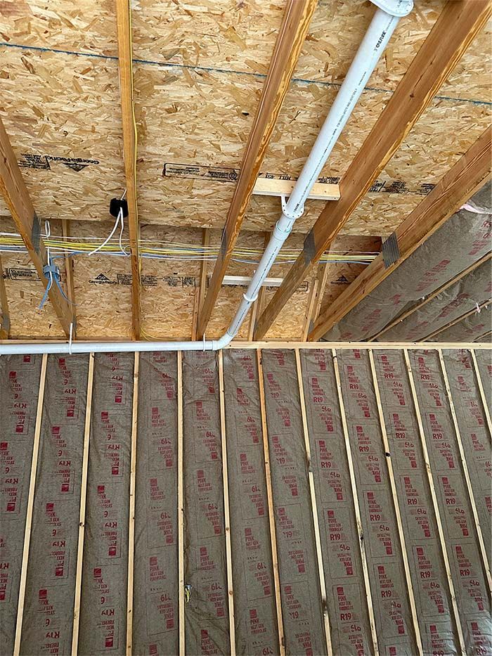 A pipe is hanging from the ceiling of a house under construction.