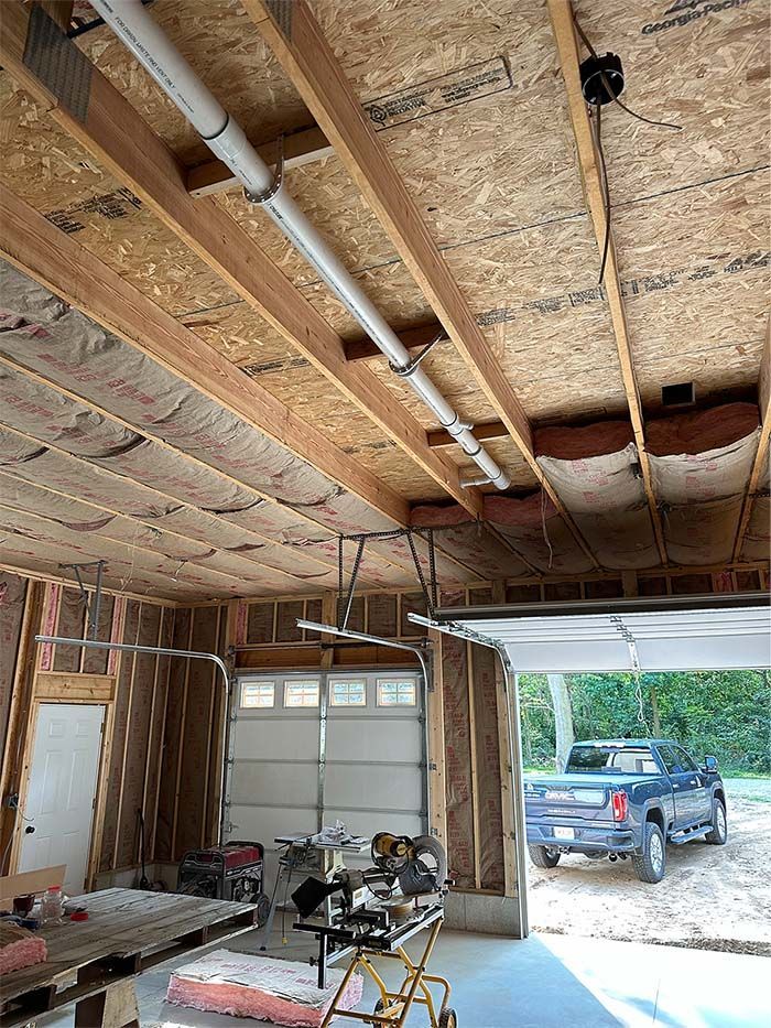 A garage under construction with a truck parked in the driveway.