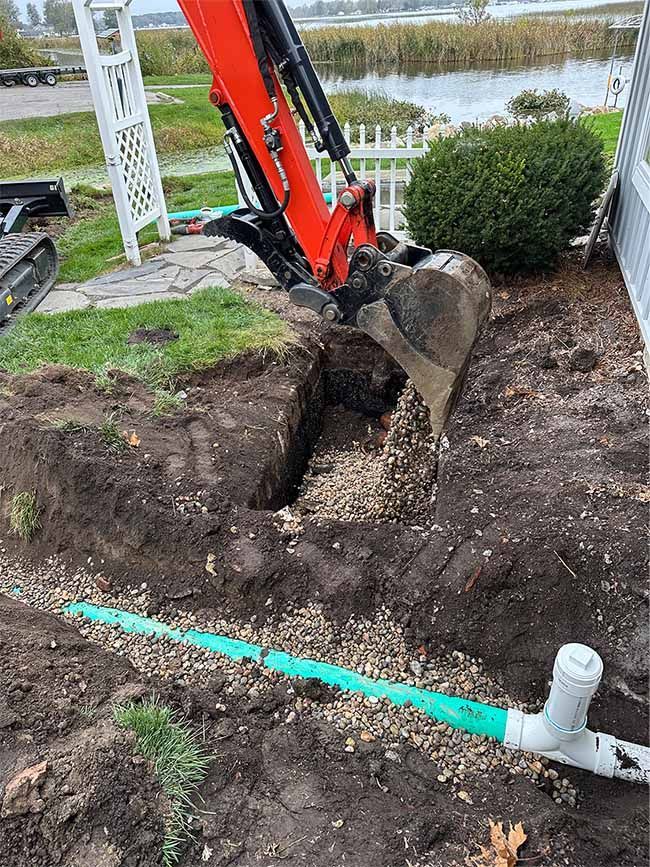 A red excavator is digging a hole in the ground next to a house.
