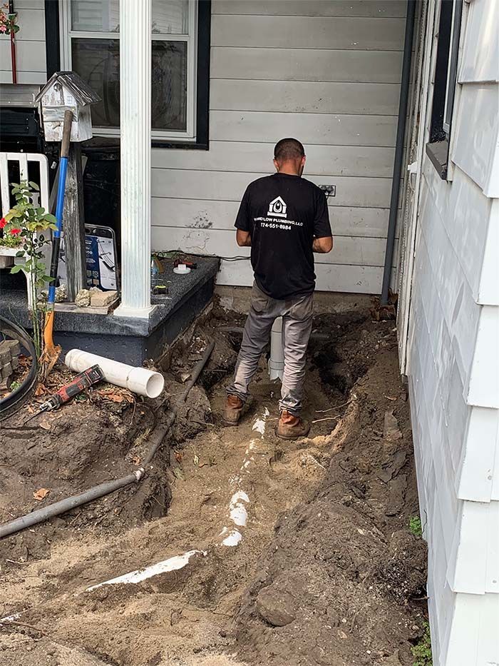 A man is digging a hole in the ground in front of a house.