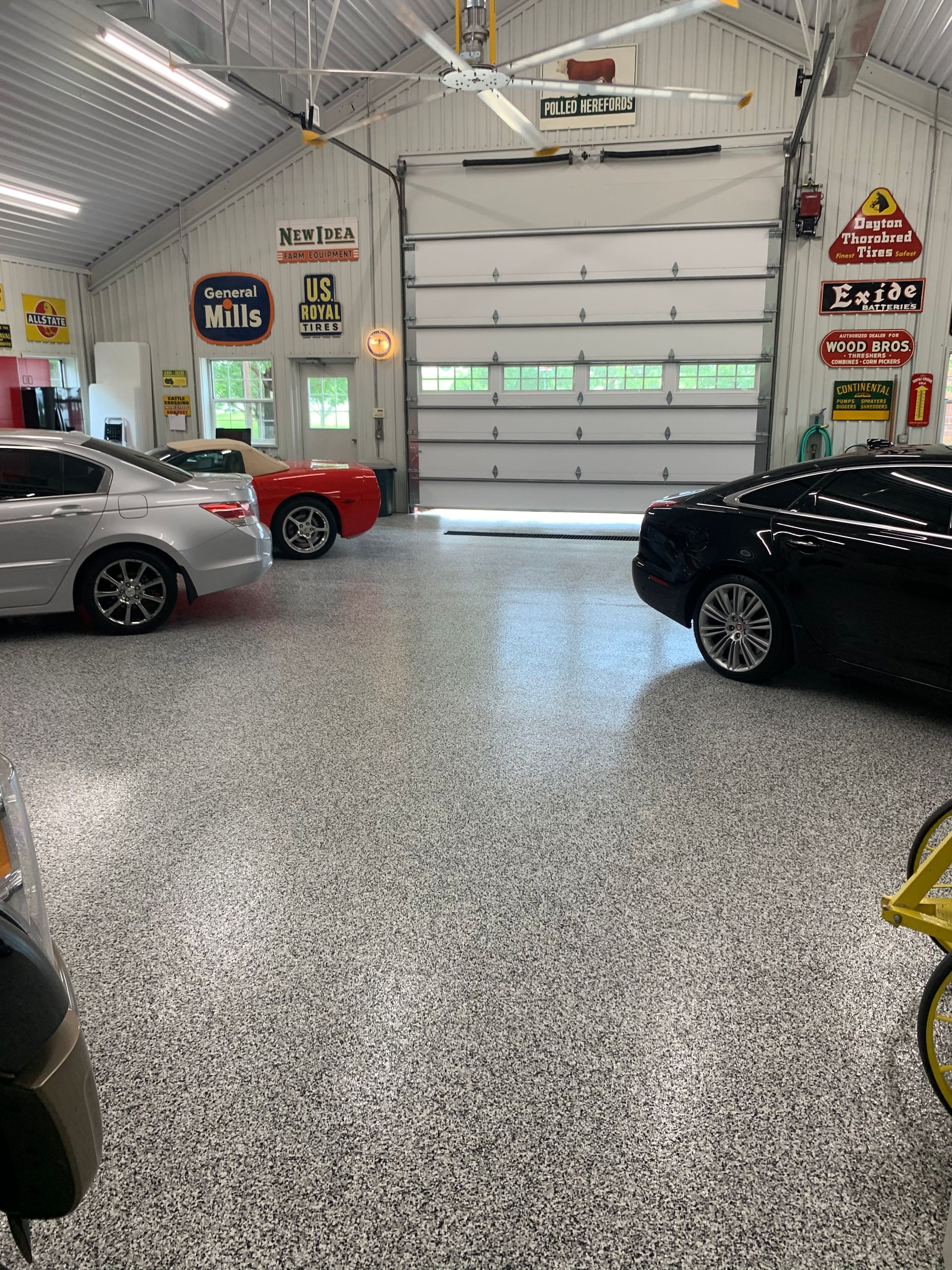 A close-up of a hand using a paintbrush to apply black paint to a stone tiled surface outdoors.