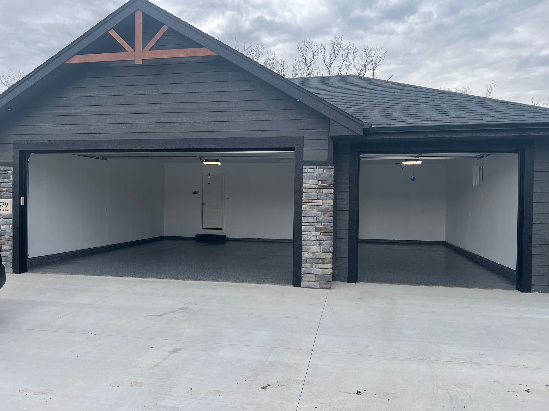 Two workers in workwear apply white coating to a flat roof with rollers, with supplies nearby on the surface.