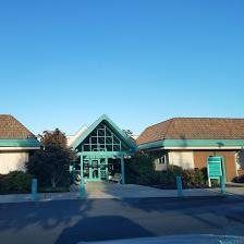 A green and white building with a blue sky in the background.