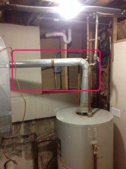 A water heater is sitting in a basement next to a pipe.