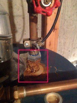 A close up of a water heater with a red valve.