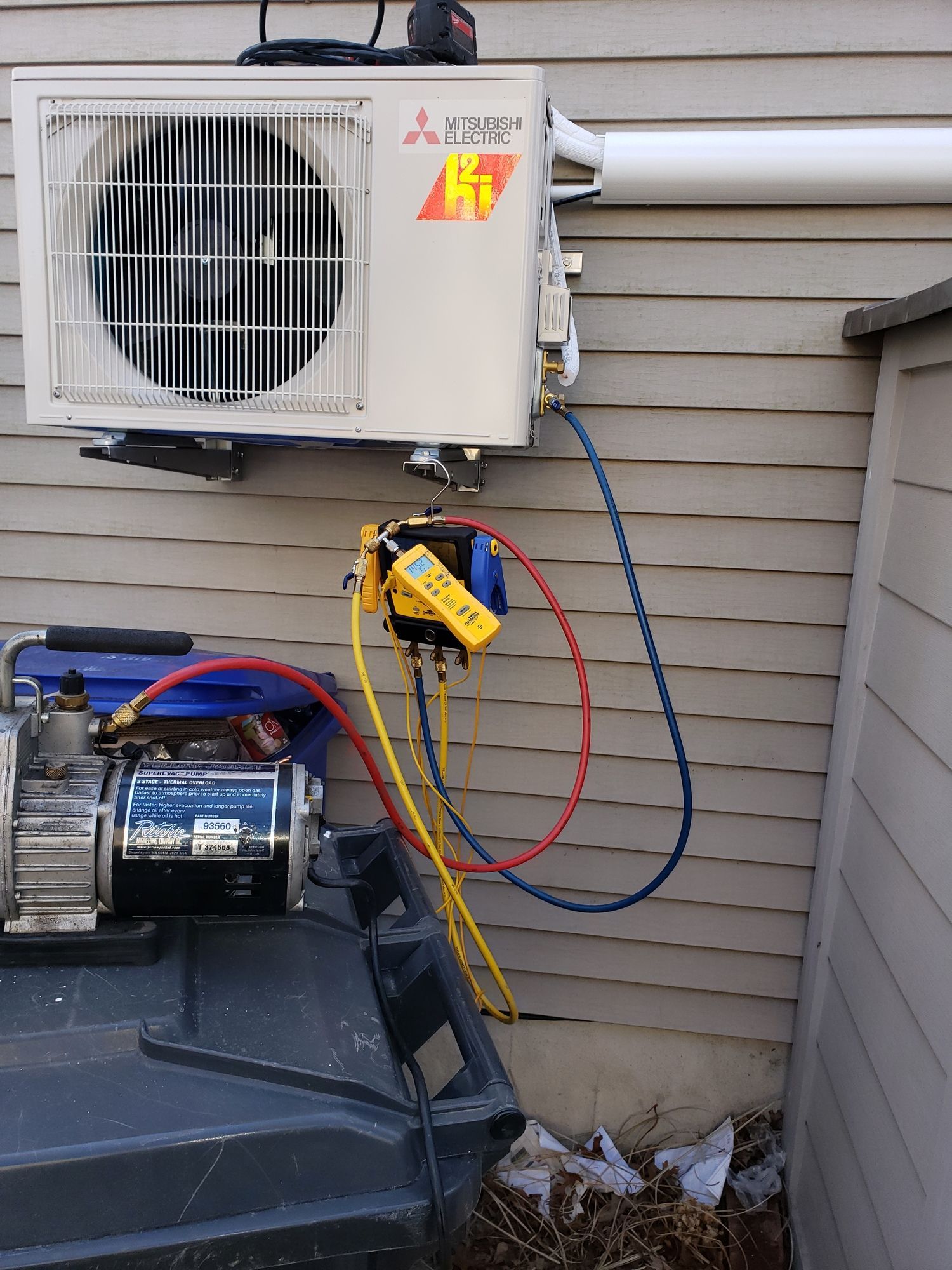 a mitsubishi air conditioner is being installed on the side of a house .