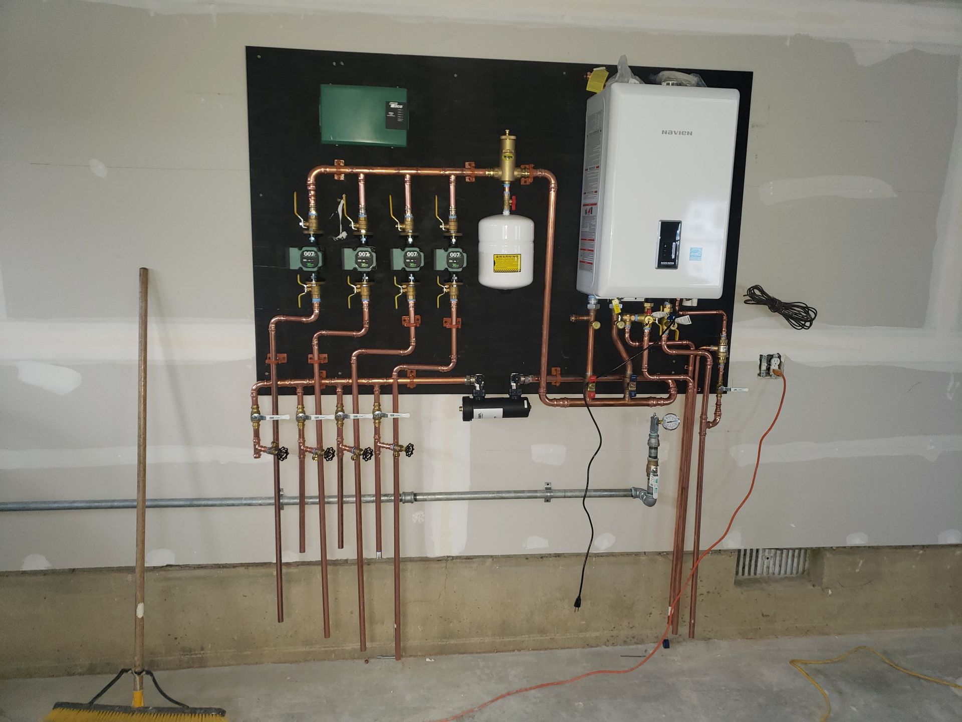 a wall with copper pipes and a boiler on it