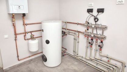 a room with a water heater and pipes on the wall .