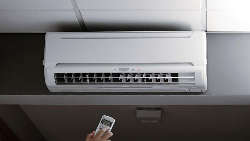 a person is using a remote control to turn on a wall mounted air conditioner .